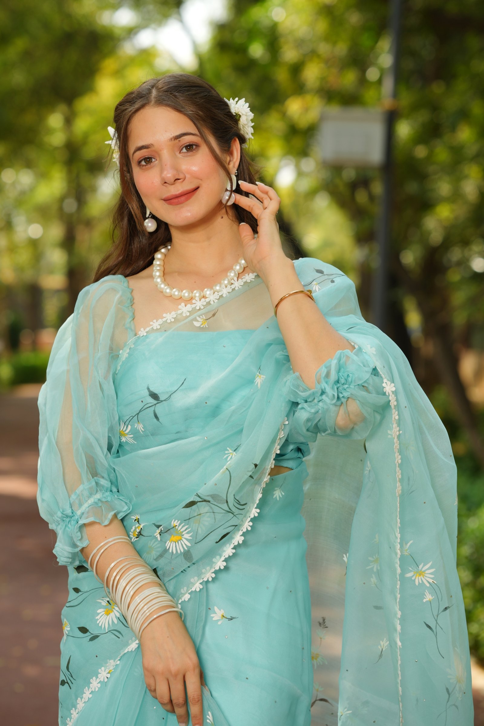 Detailed shot of the handpainted daisy motifs and the scalloped lace border on the aqua pure organza saree.