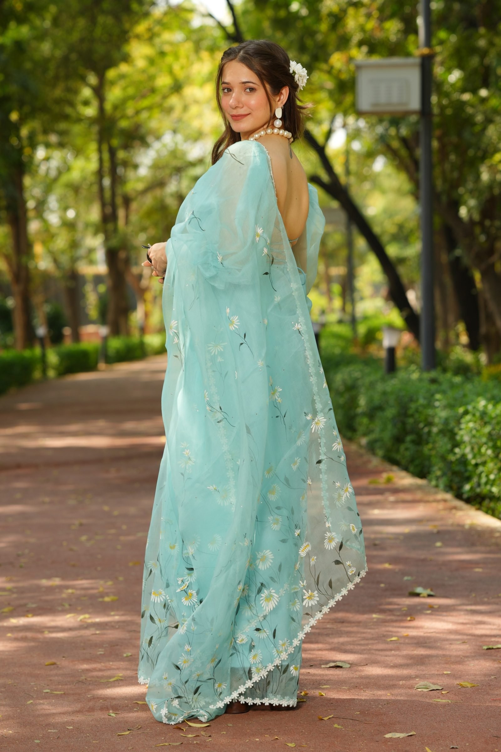 Indian woman posing in Azure Daisy Handpainted Saree, showcasing the full flow of the pure organza silk.