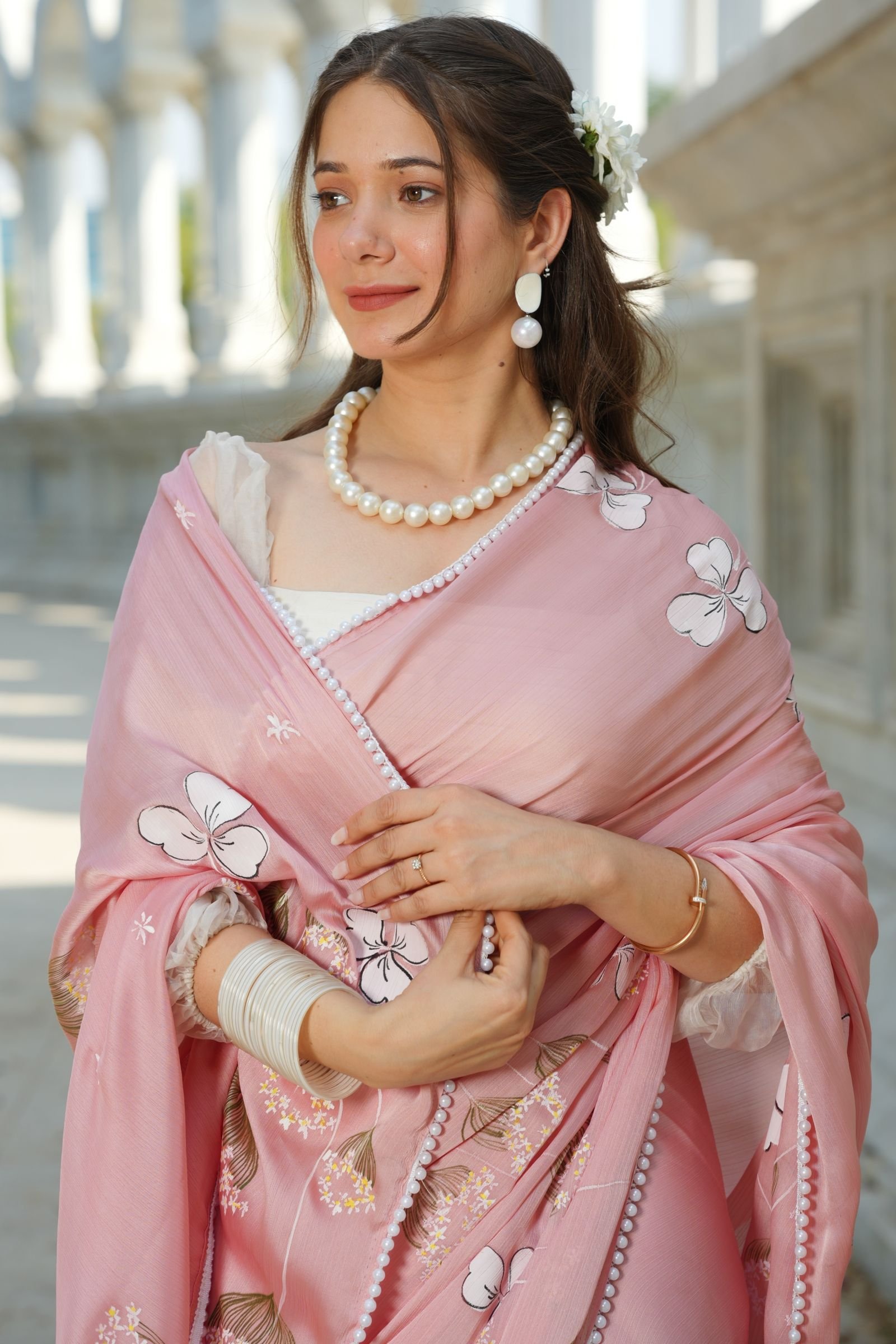 Detailed shot of the pearl bead lace border and the white floral handpainting on the luxury pink silk fabric.