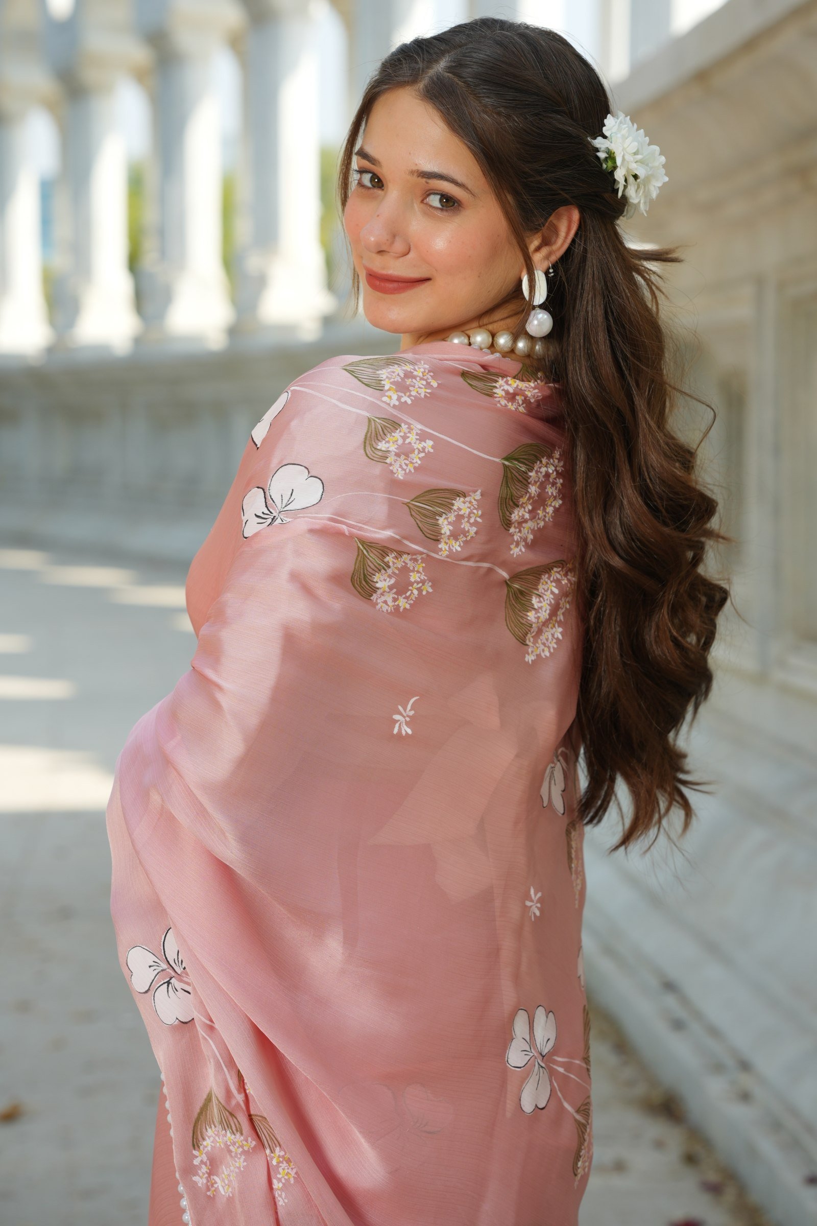 Close-up of the handpainted white blossoms and trailing foliage on the blush pure silk saree.