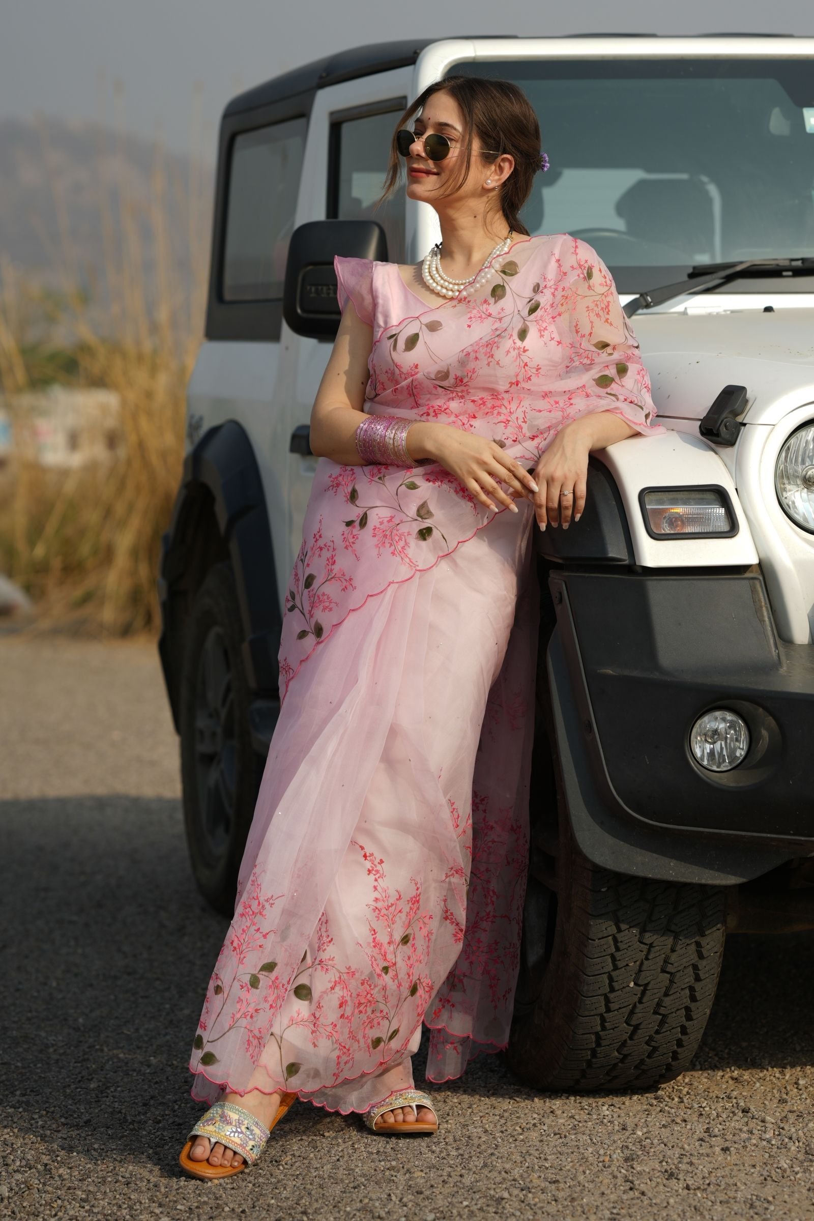Indian woman posing in the Pink Cherry Blossom Organza Saree, showing the full drape and handpainting detail.