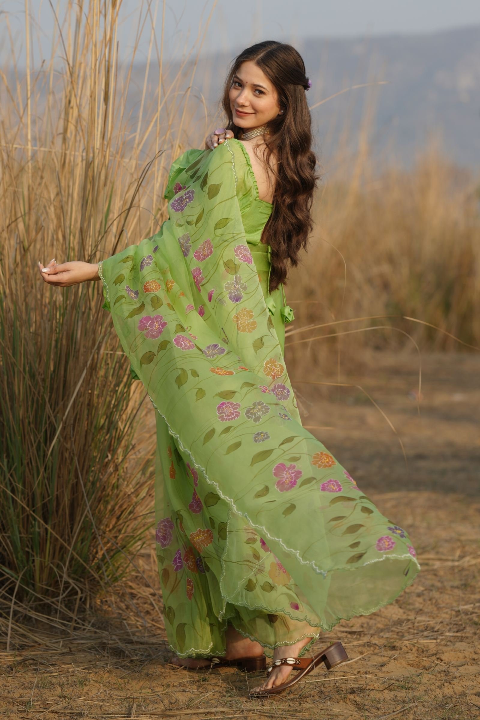 Indian woman posing in the Lime Green Organza Saree, showing the flow and detailed hand-beaded scalloped border.