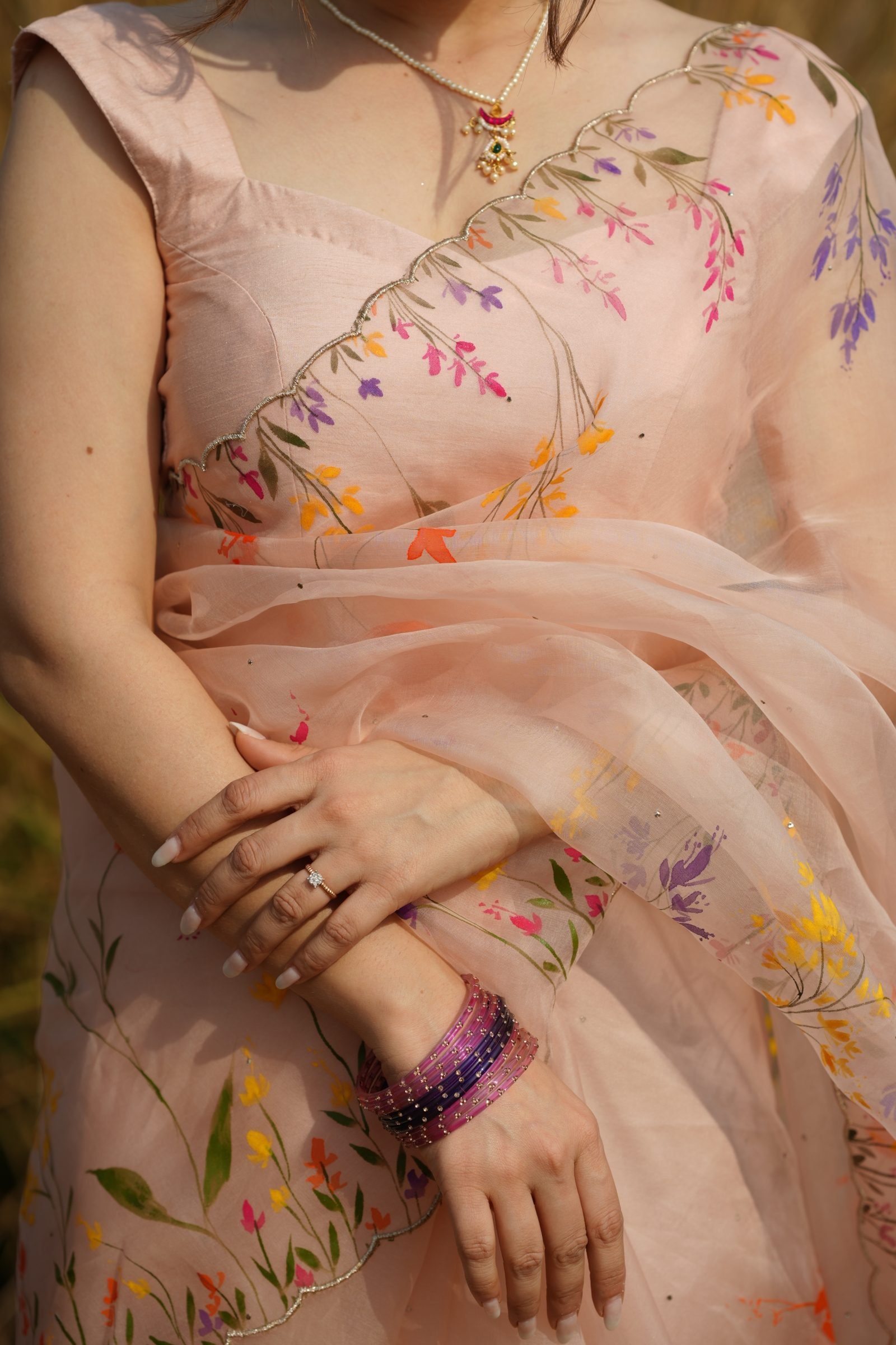 Fabric detail of the scalloped border and colorful wildflower brushwork on the Light Peach Organza Saree.
