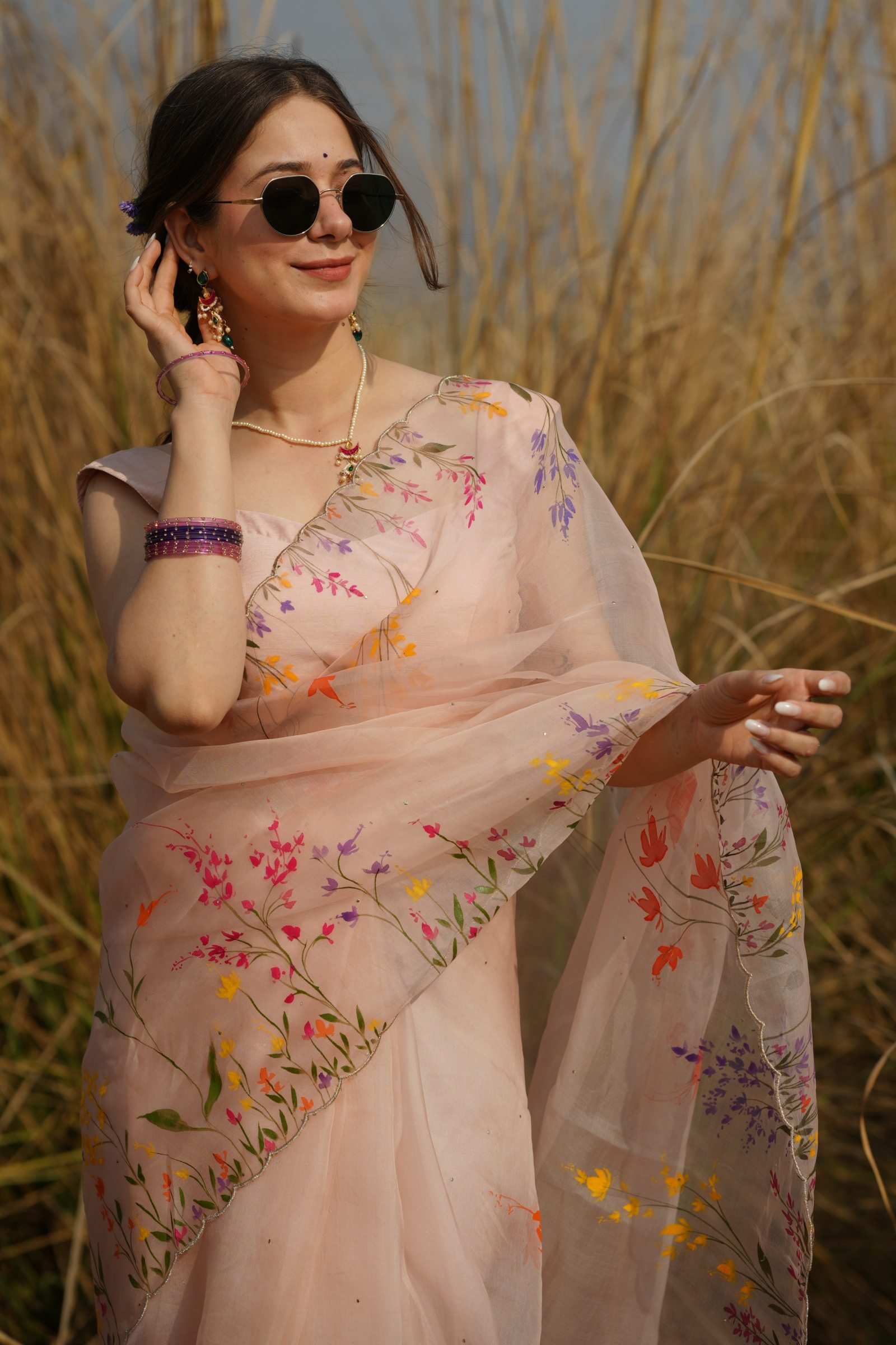 Close-up of model in the Peach Wildflower Organza Saree, showing the vibrant lavender, yellow, and orange handpainted wildflowers.